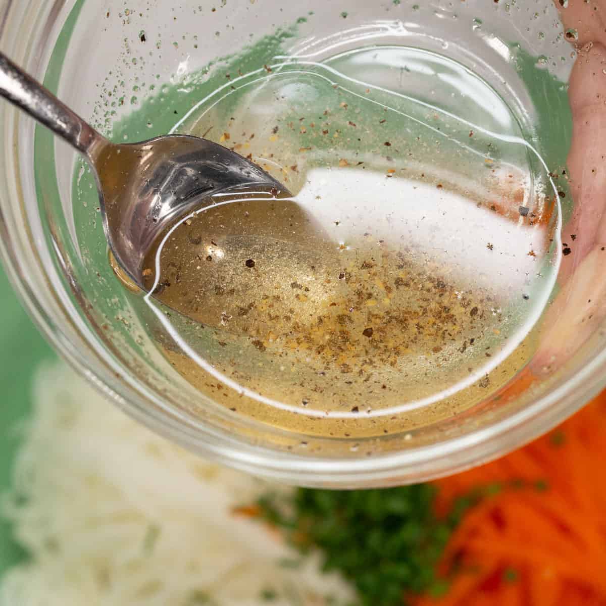 Mixing the vinegar-based dressing in a bowl over the salad.