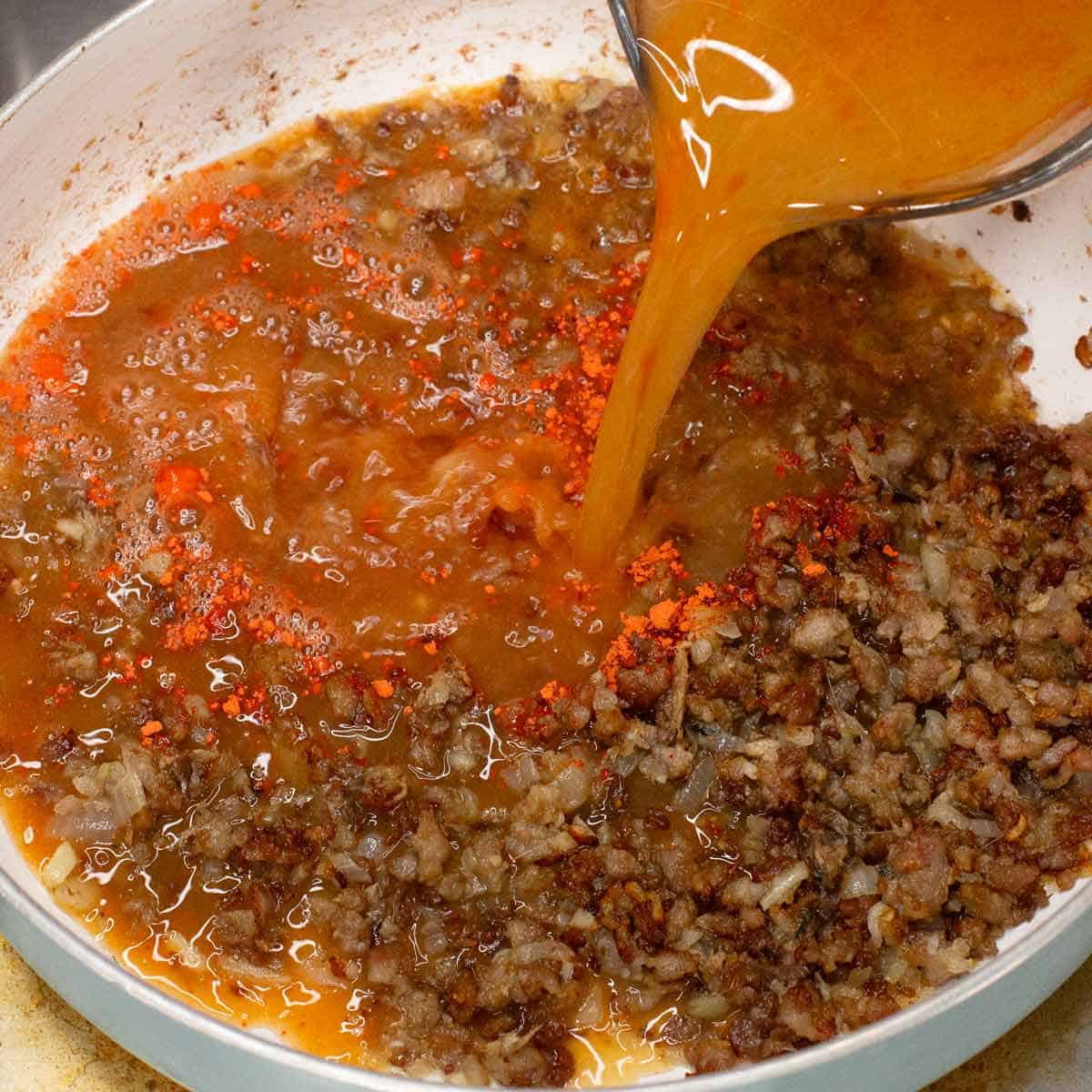 Adding the shrimp stock to the pan with the other ingredients.