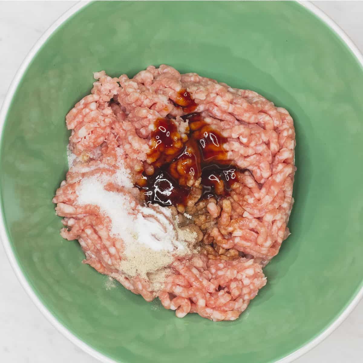 Mixing ground pork and seasonings in a bowl.