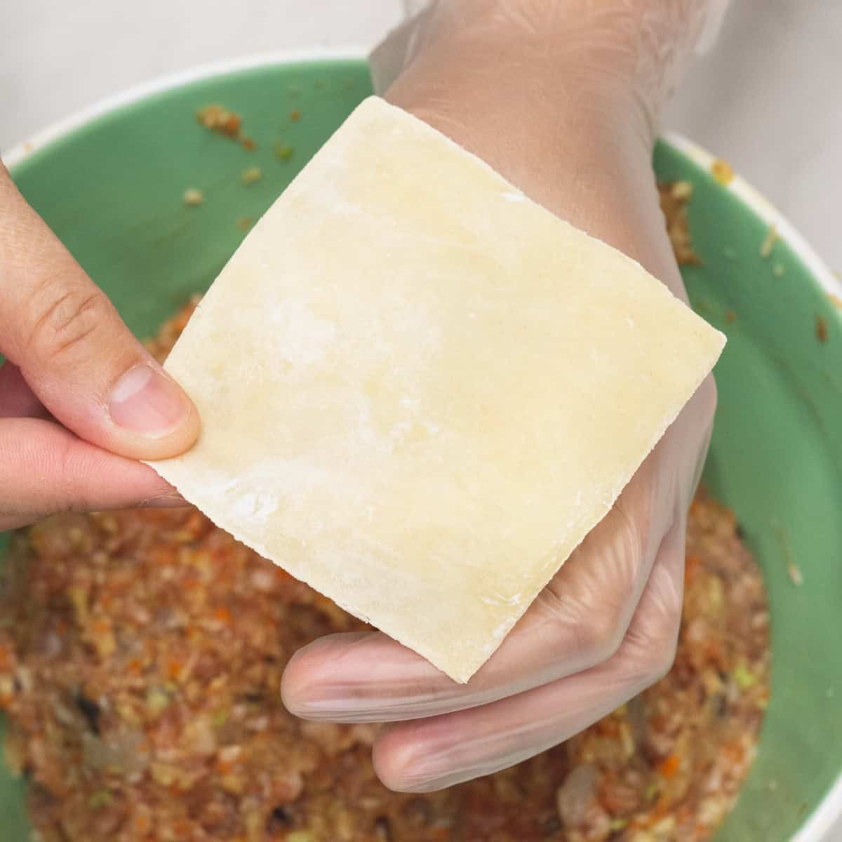 Wrapping the siomai by first forming an "o" with thumb and index finger, then placing a wrapper over it