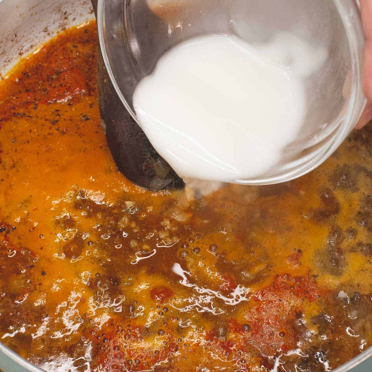 Adding cornstarch slurry to the mixture to thicken the sauce.