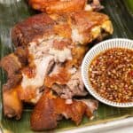 Crispy pata with dipping sauce on a plate with banana leaf.