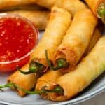 Dynamite lumpia recipe with a Sweet and Chili dipping sauce on a plate.