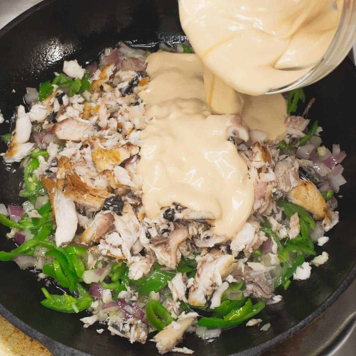 Added the bangus meat and sauce to the aromatics and peppers in the skillet.