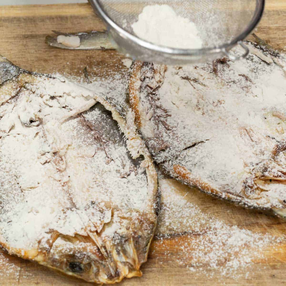 Coating the skin of the bangus with flour.