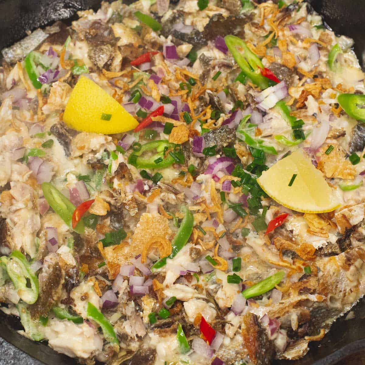 Added garnishes to the Bangus Sisig in the skillet.