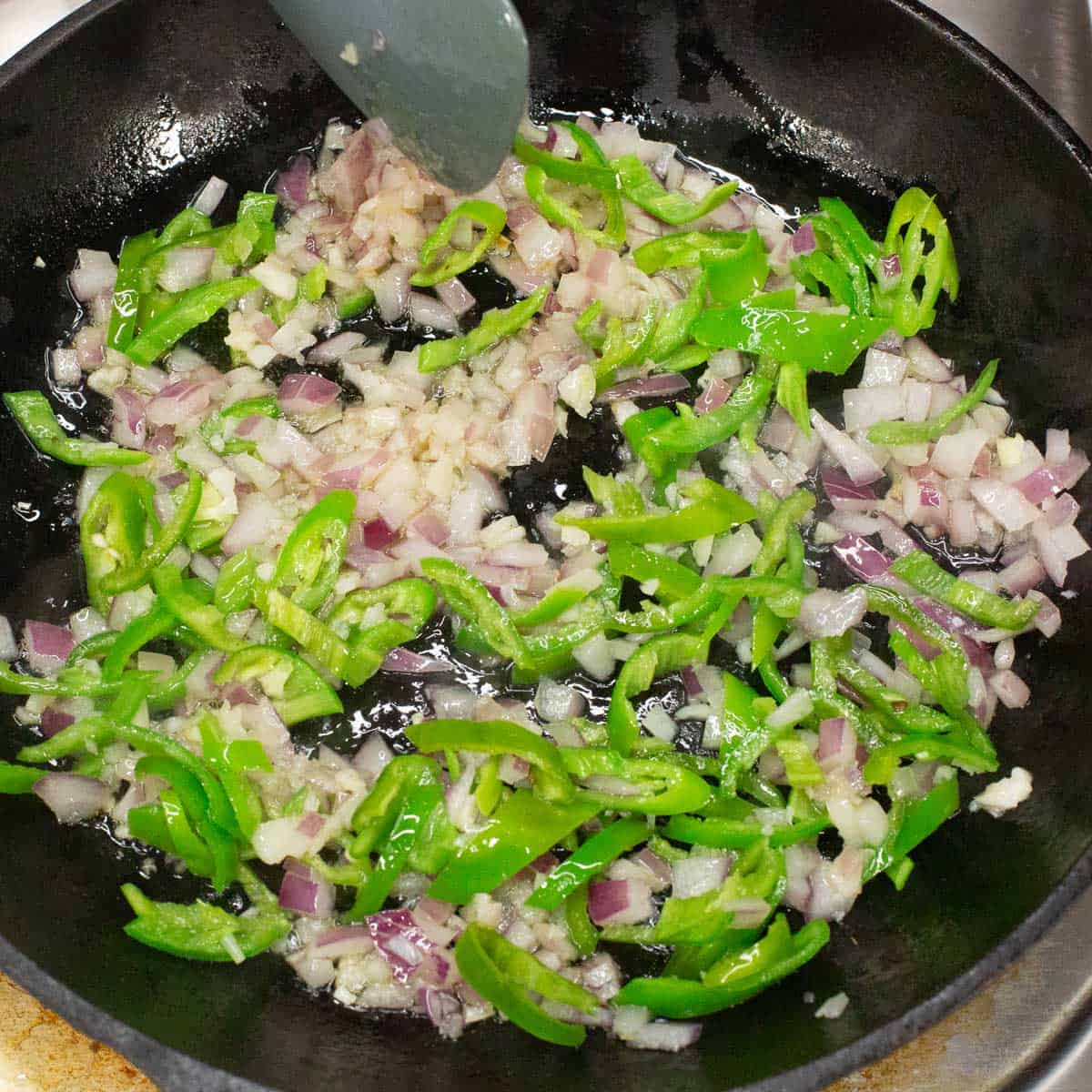 Sauteing the aromatics and peppers in the skillet.