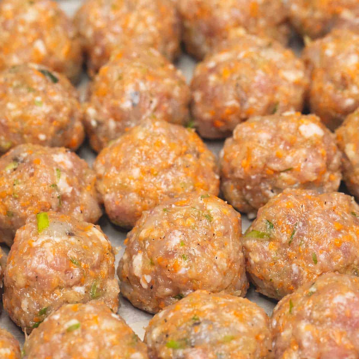 Shaping the meatballs and placing them on a baking sheet.