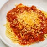 Filipino Spaghetti topped with grated cheese on a plate.
