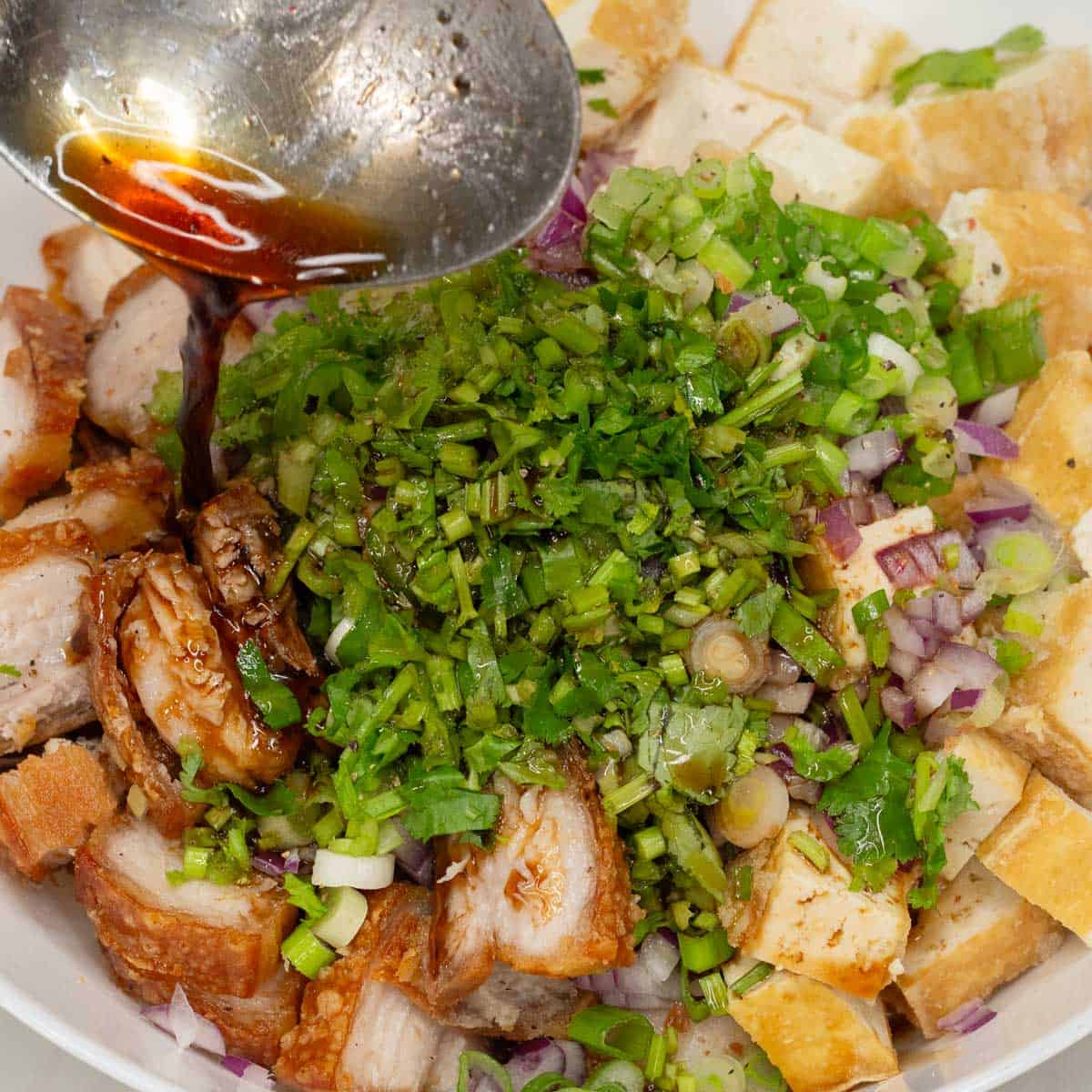 Combining the ingredients for Tokwa't Baboy in a bowl, then adding the sauce.