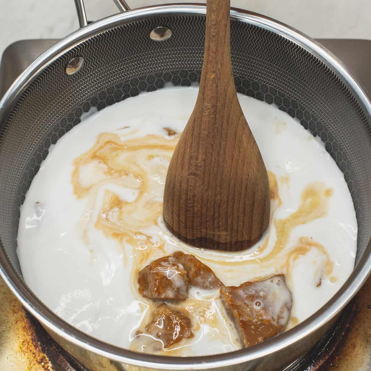 Mixing coconut milk and panutsa in a saucepan