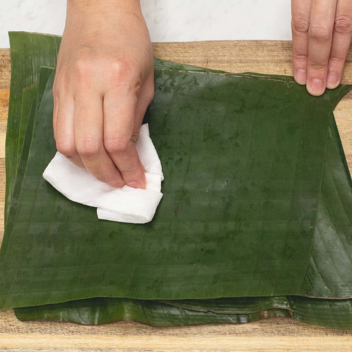 Preparing the banana leaves by wiping it with a papertowel