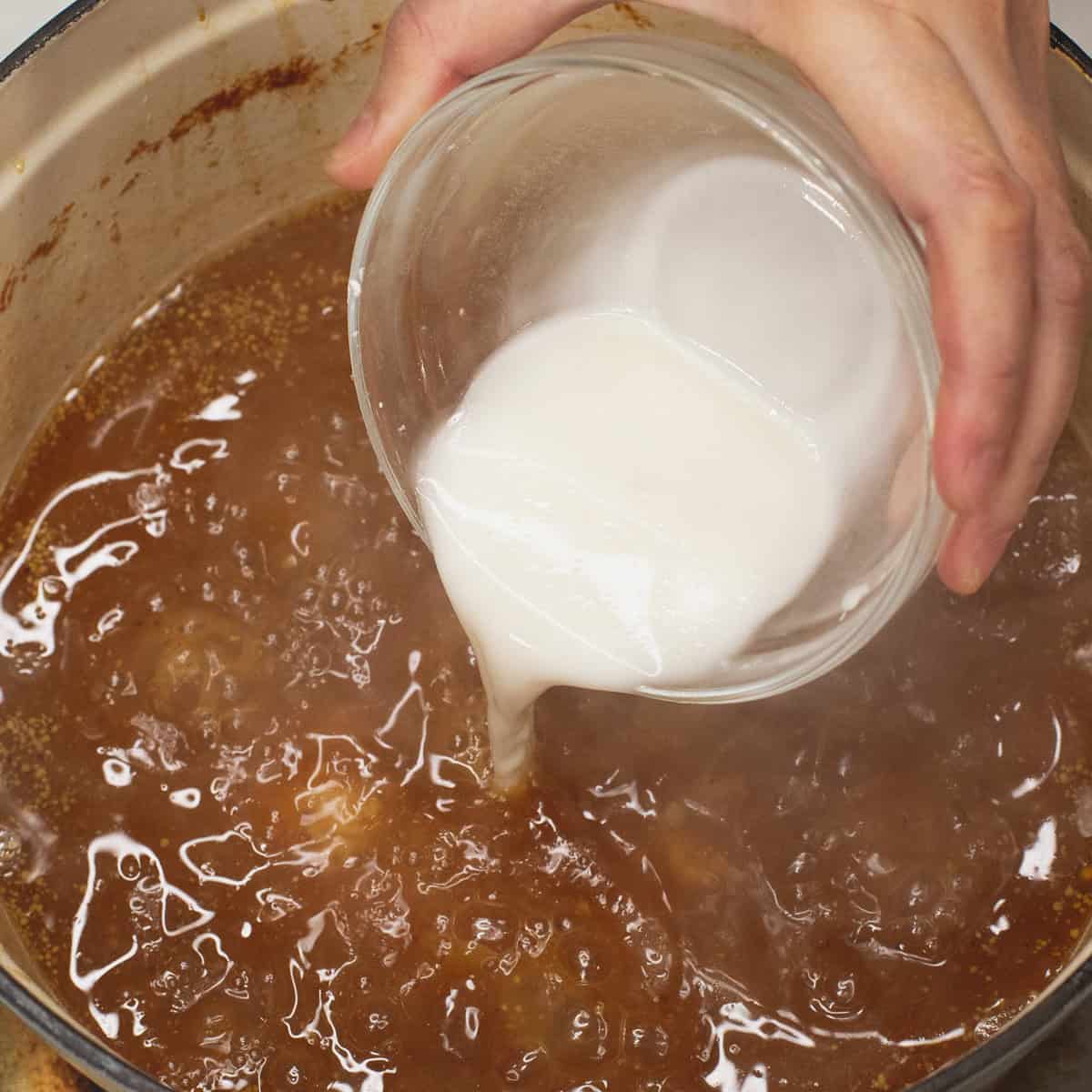 Thickening the sauce with a cornstarch slurry.