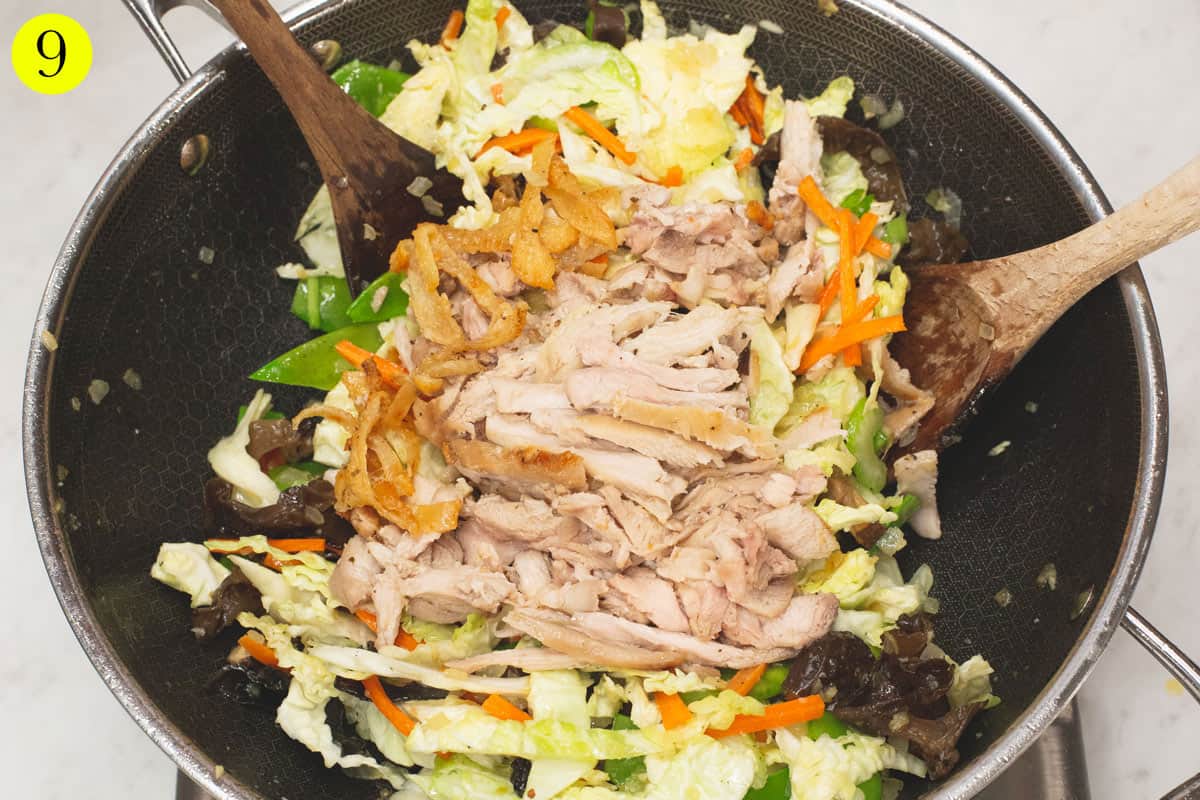 Added the shredded chicken to the aromatics and vegetables in a wok.