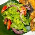 Ampalaya Salad with fried bangus on a plate with banana leaf.
