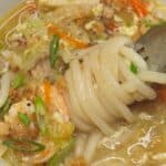 Lomi in a bowl with a fork swirled with noodles.