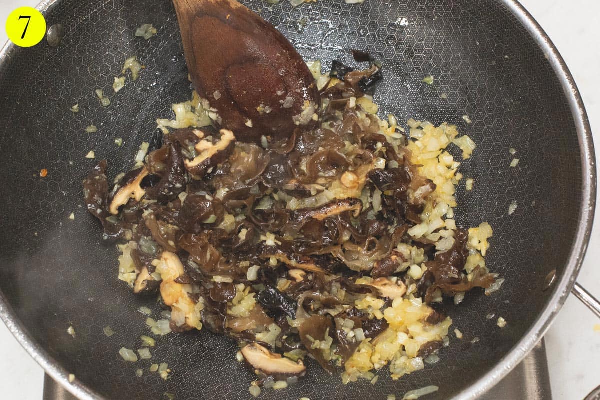 Sauteing the aromatics and mushrooms in a wok.
