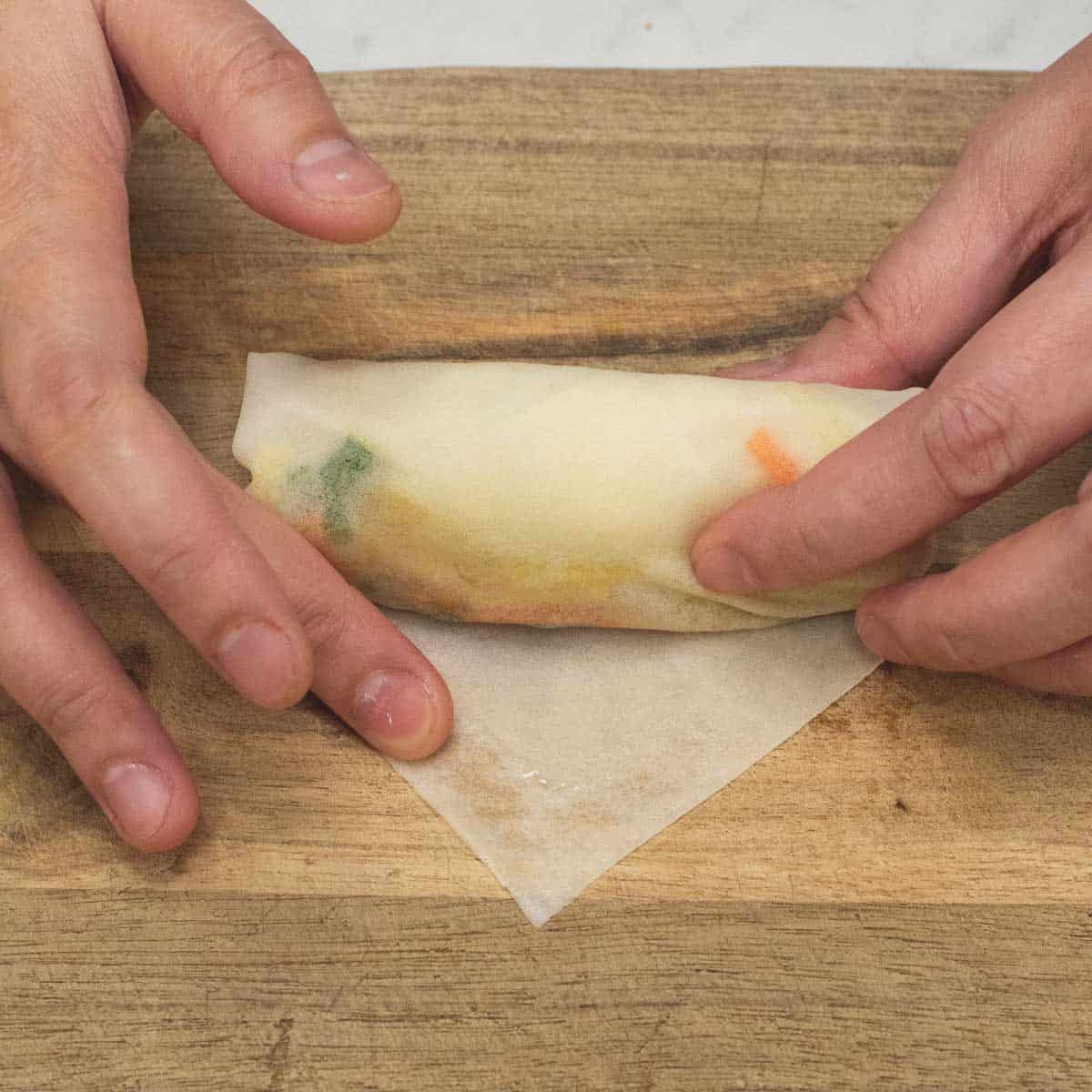 Rolling tightly and sealing the edge with water or egg wash.