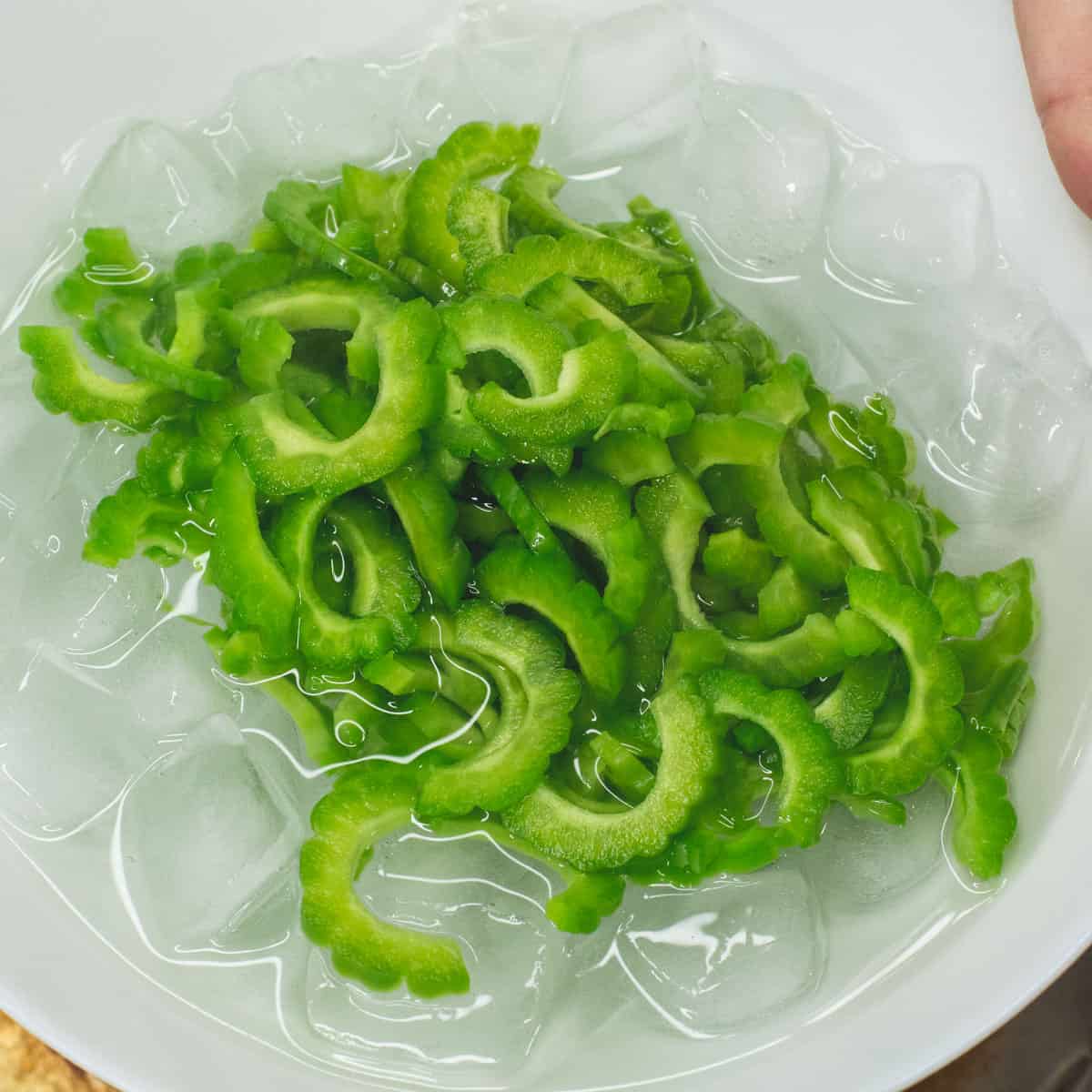 transferring ampalaya to a bowl of water with ice.