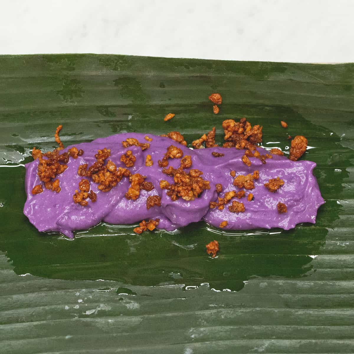 Placing about 3 tablespoons ube mixture on the lower part of the leaf
