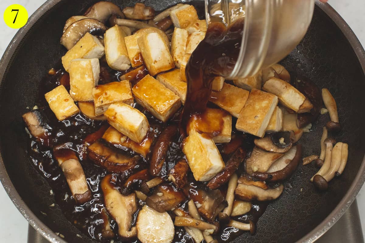 Pouring the adobo sauce over the tofu and mushrooms in the skillet.