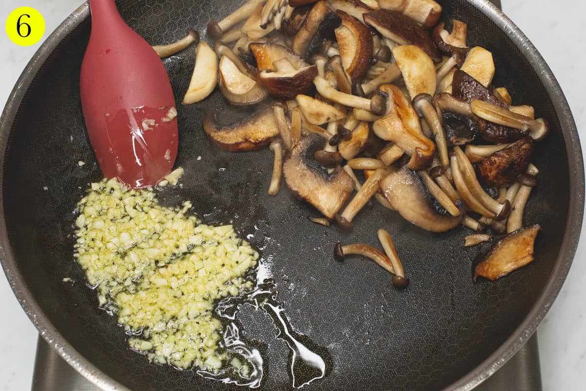 Sauteing the garlic on one side of the pan, with the seared mushrooms on the other side.