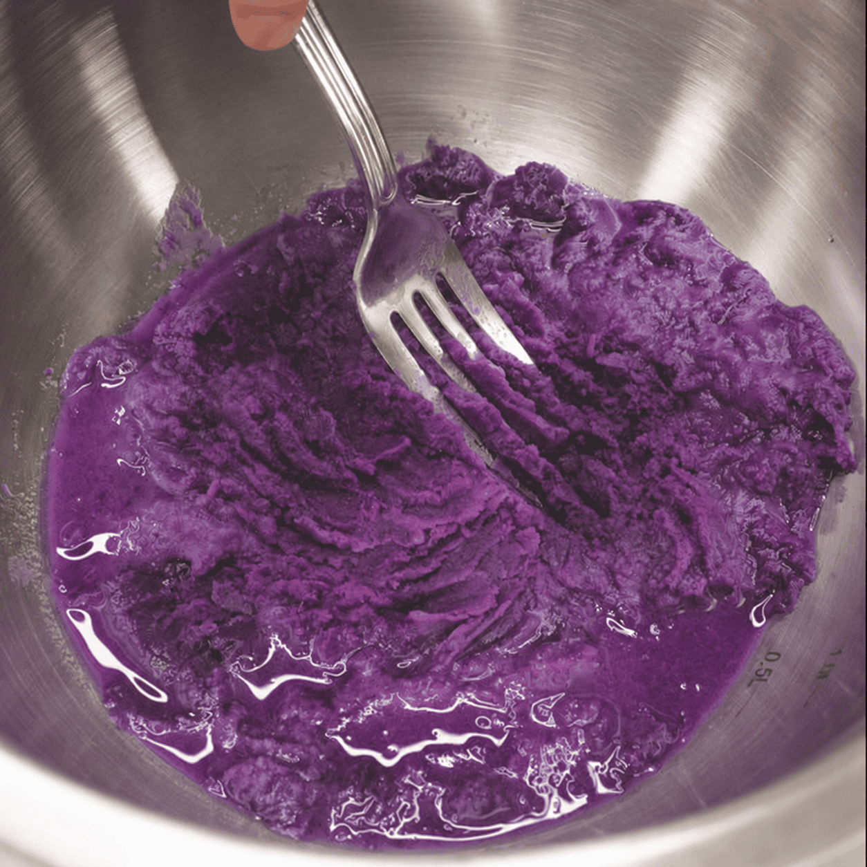 Mashing ube in a mixing bowl.