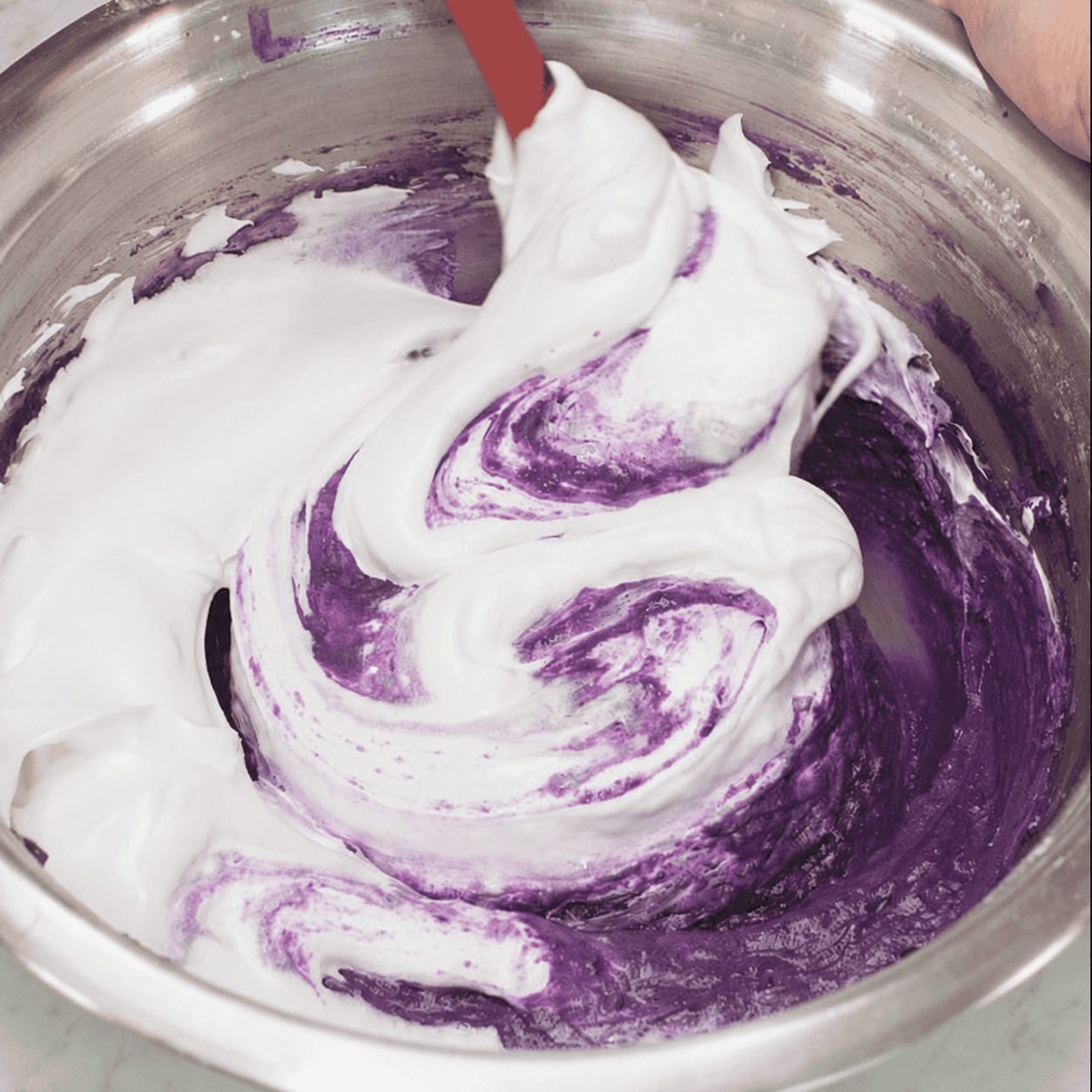 Folding white meringue into the purple ube batter.