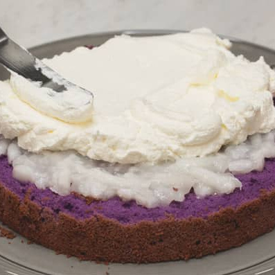 Spreading whipped cream over macapuno on the first cake layer.