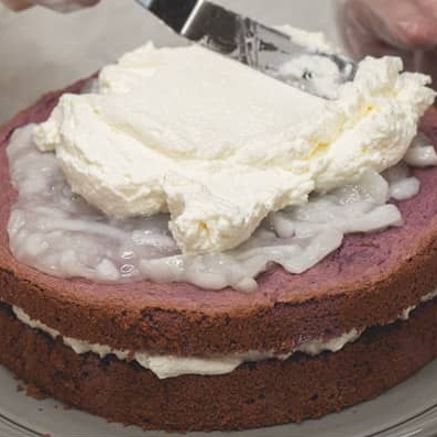 Adding macapuno and whipped cream to the second cake layer.