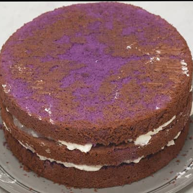 Three ube cake layers stacked with filling.