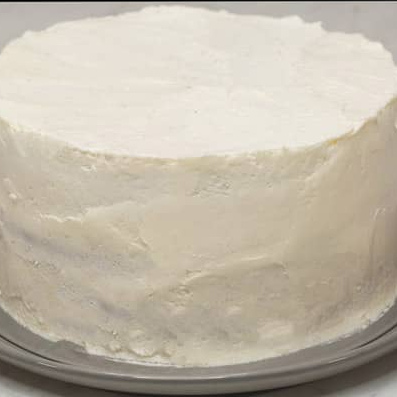 Assembled ube cake covered with whipped cream frosting.