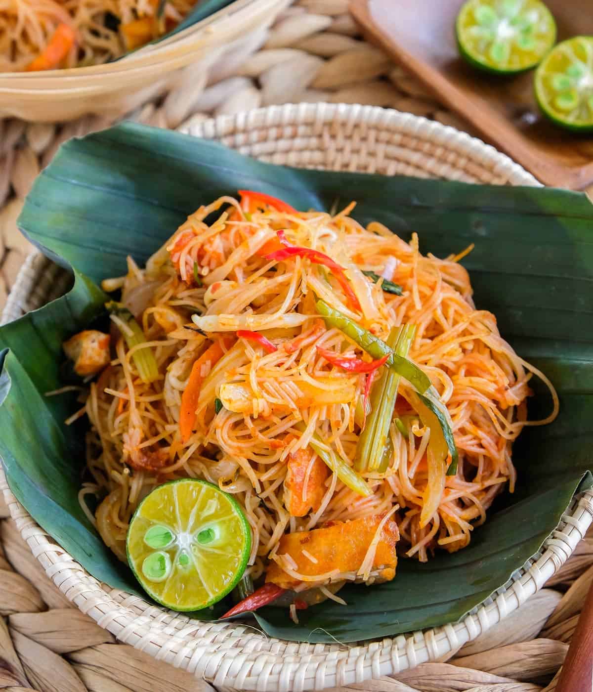 Rice noodles on a banana leaf-lined basket with calamansi on the side.