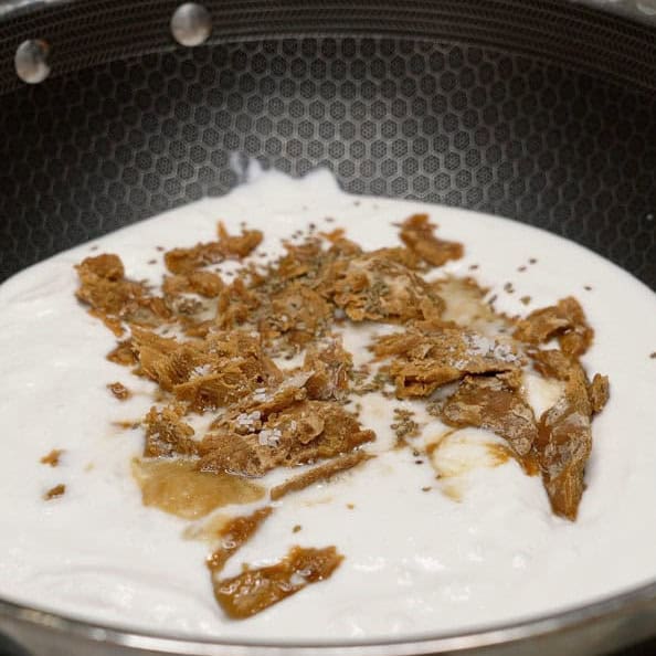 Coconut milk, chopped panutsa, and seasonings in the pan.