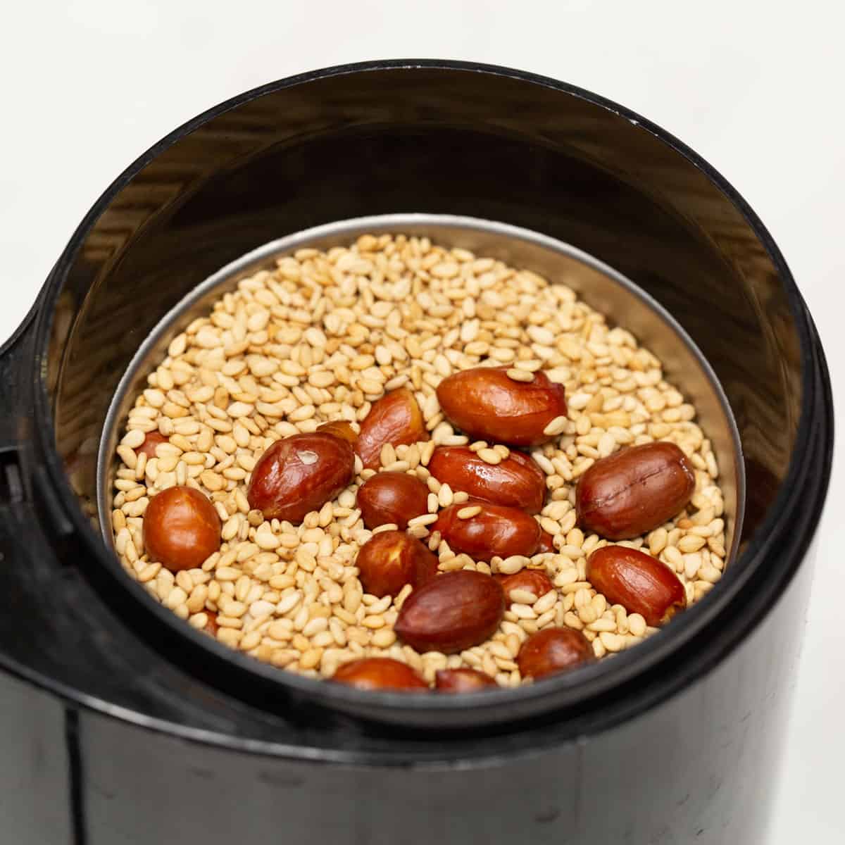 Combining peanuts and sesame seeds in a coffee grinder.
