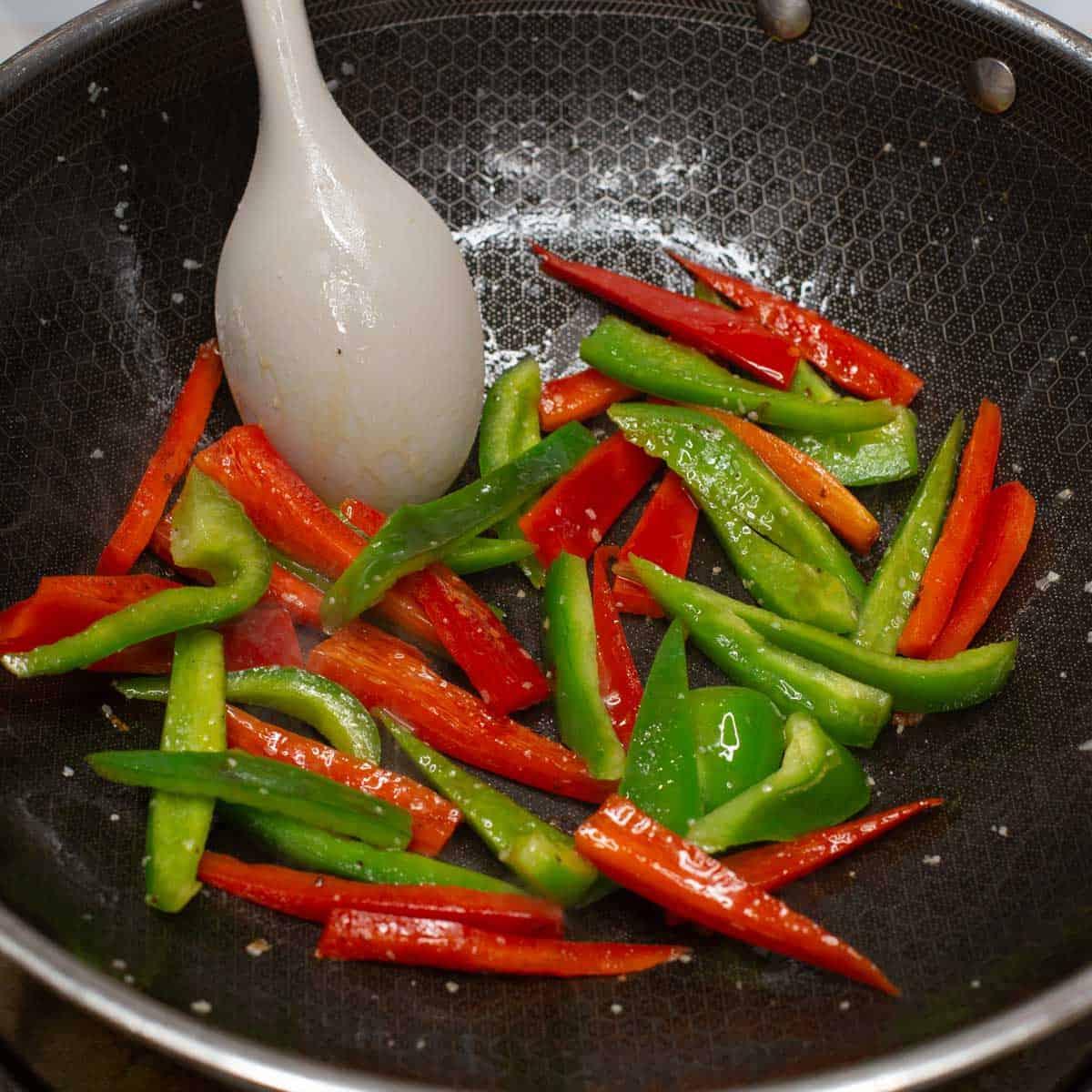 sauteing red and green bell peppers in a wok