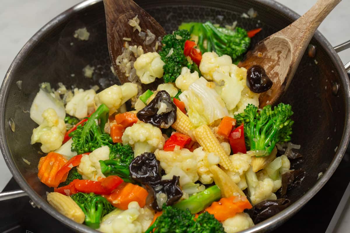 Stir-frying firm vegetables in a wok.