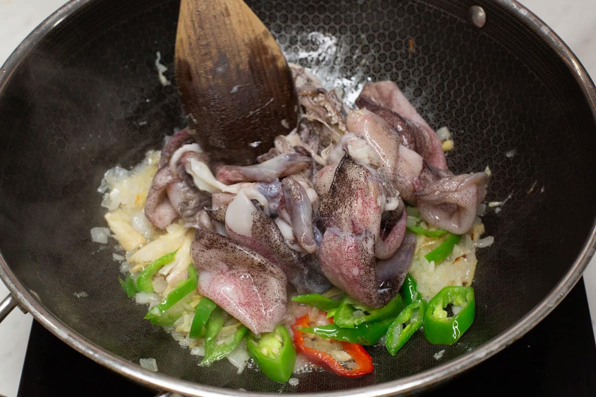 Added squid to the aromatics in the wok.