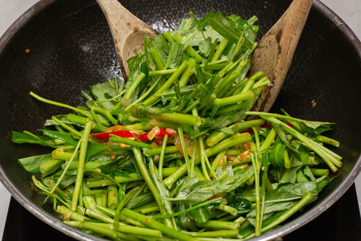 Tossing the kangkong stems in a wok.