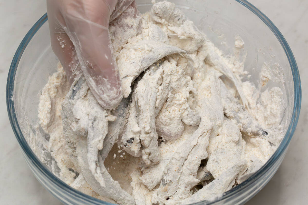 Coating the fish with the flour mixture.