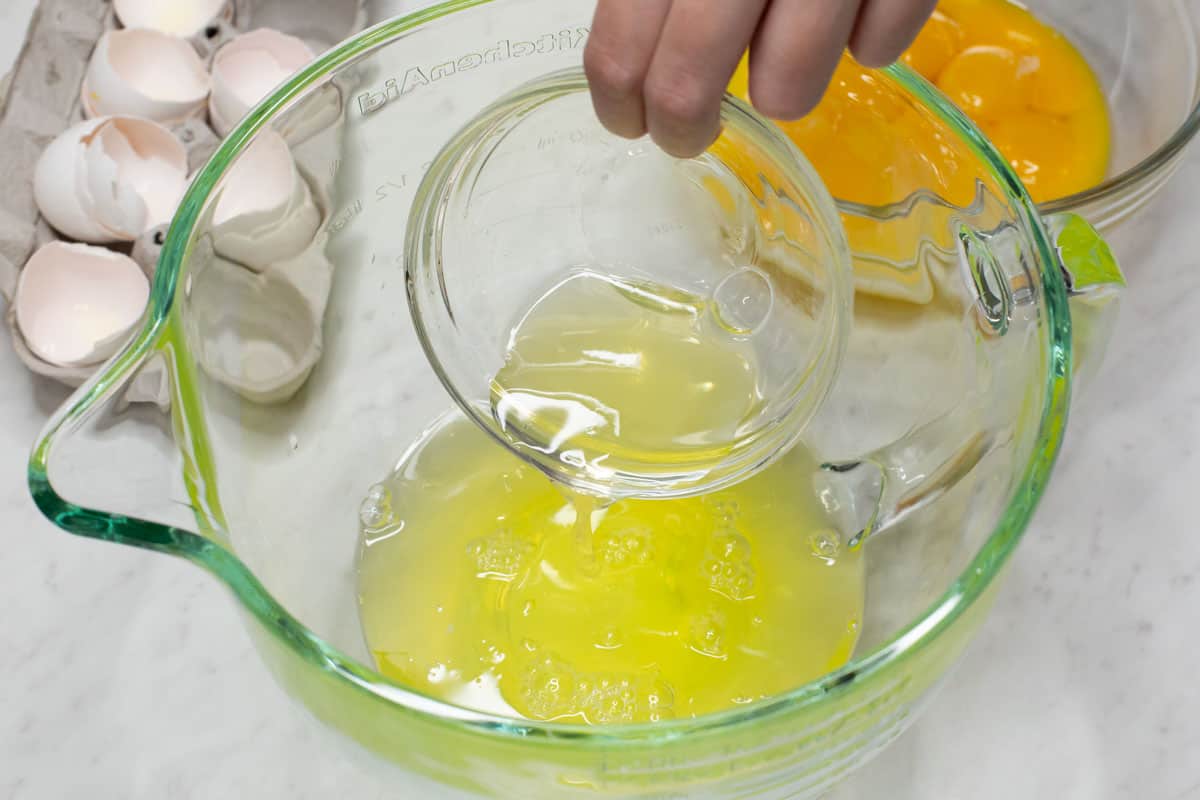 Adding egg whites from the smaller bowl to the larger one.