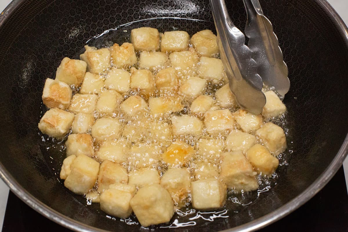 Frying the tofu pieces in a wok.