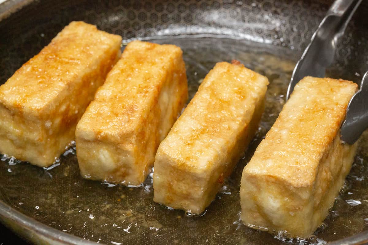 Frying the tofu in a skillet.