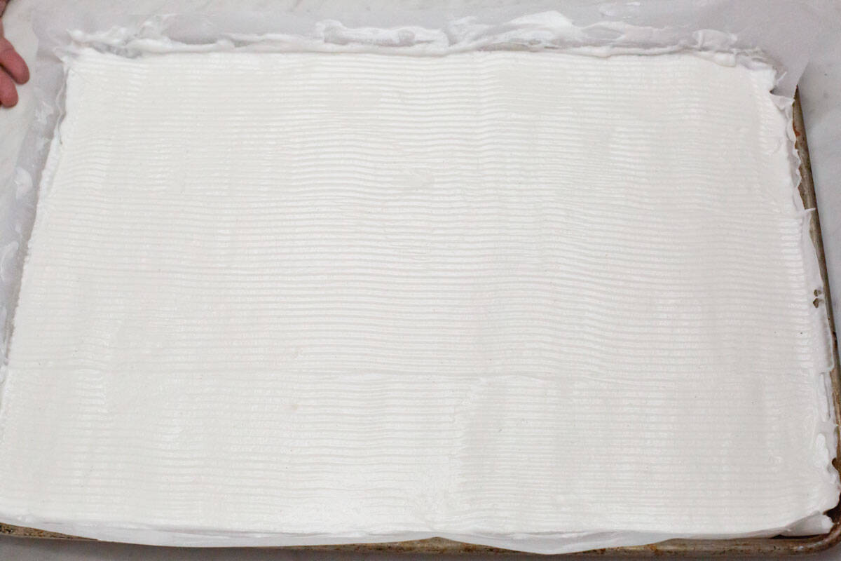 Meringue spread over the baking sheet with ridges on top.