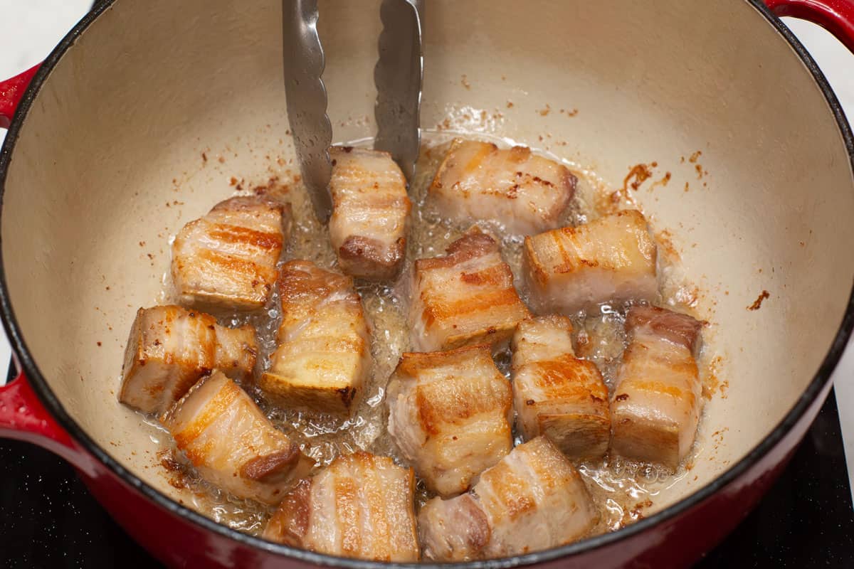 Searing the pork belly in the pot.