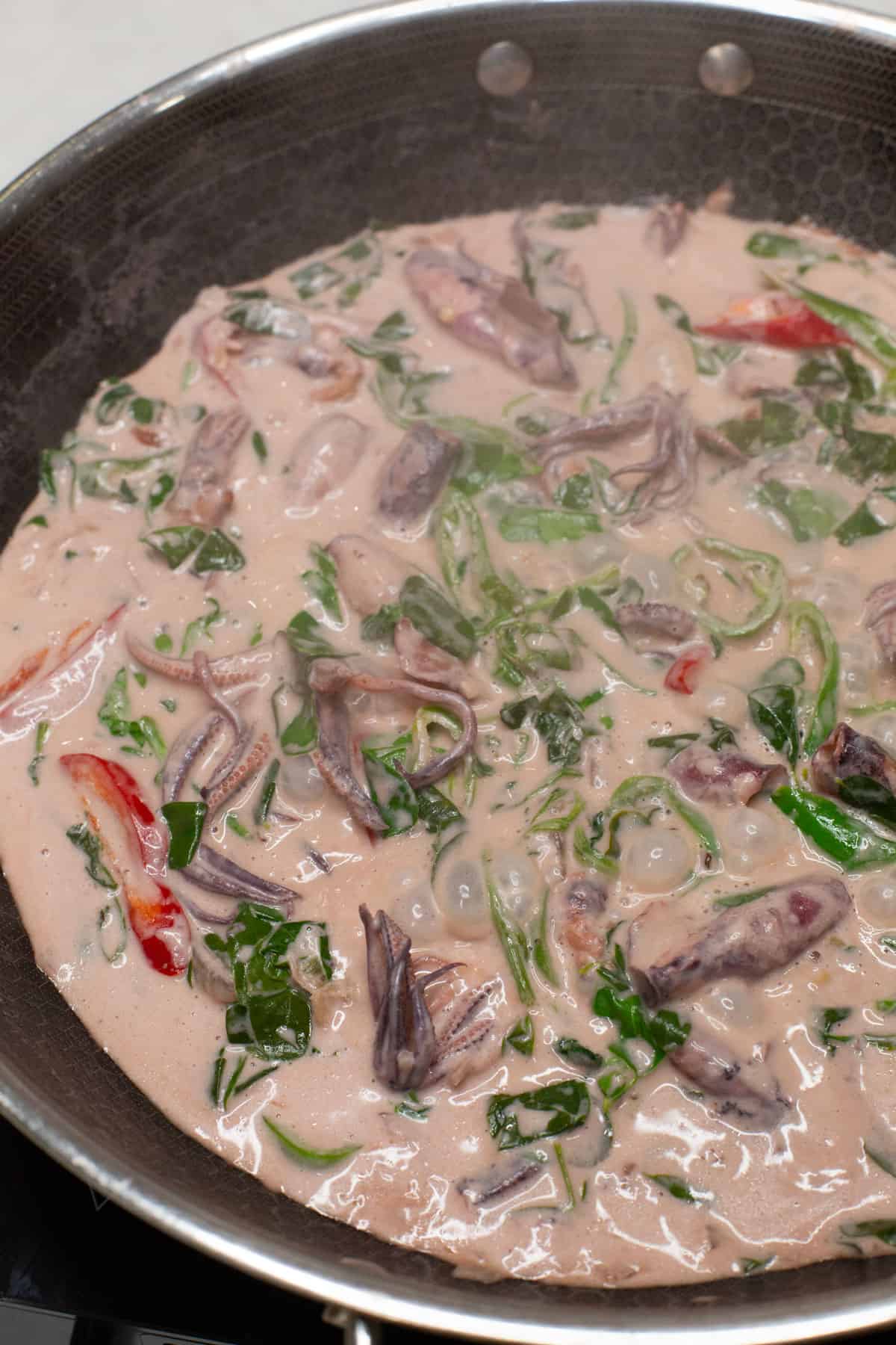 Simmering Ginataang Pusit with Malunggay in a wok.