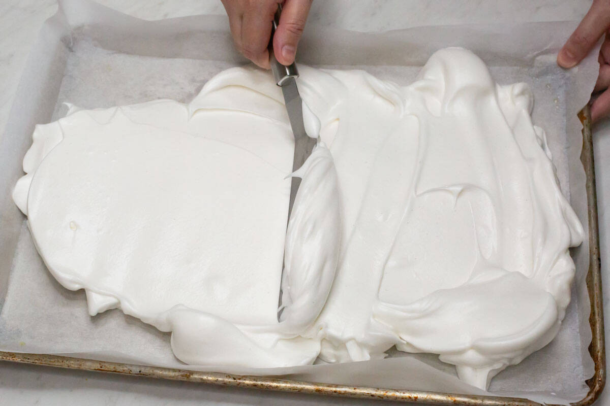 Spreading the meringue on the baking sheet using an offset spatula.