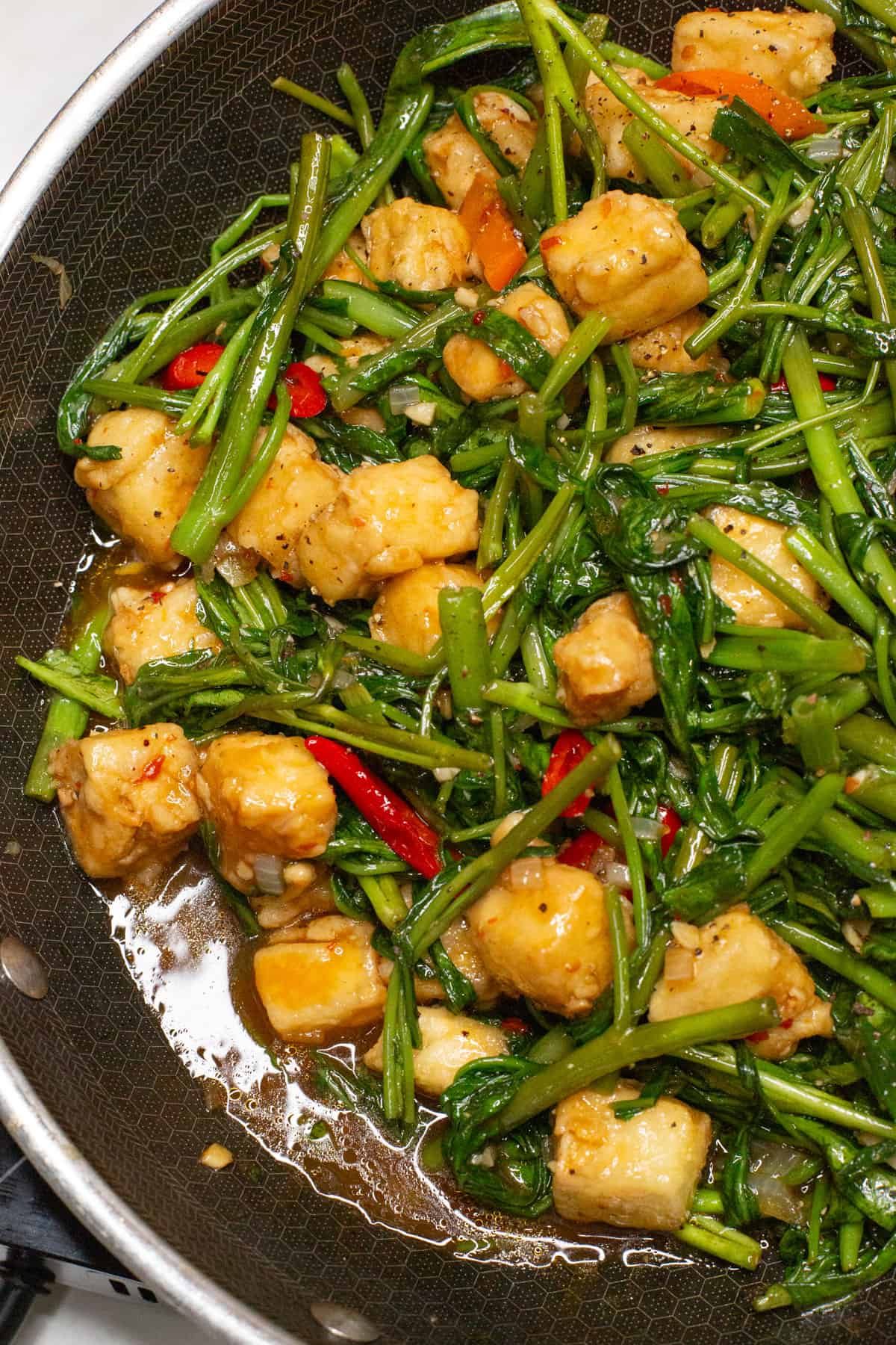 Stir-fried Kangkong and Tofu in a wok.