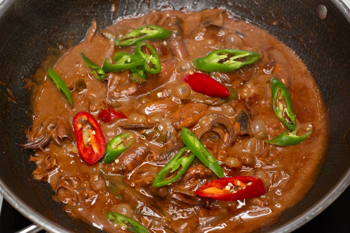 Adobong Pusit sa Gata with sliced chilies on top in a wok.