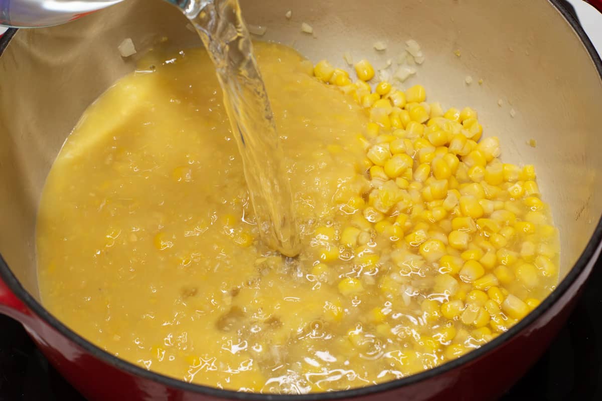 Adding water to the corn in the pot.